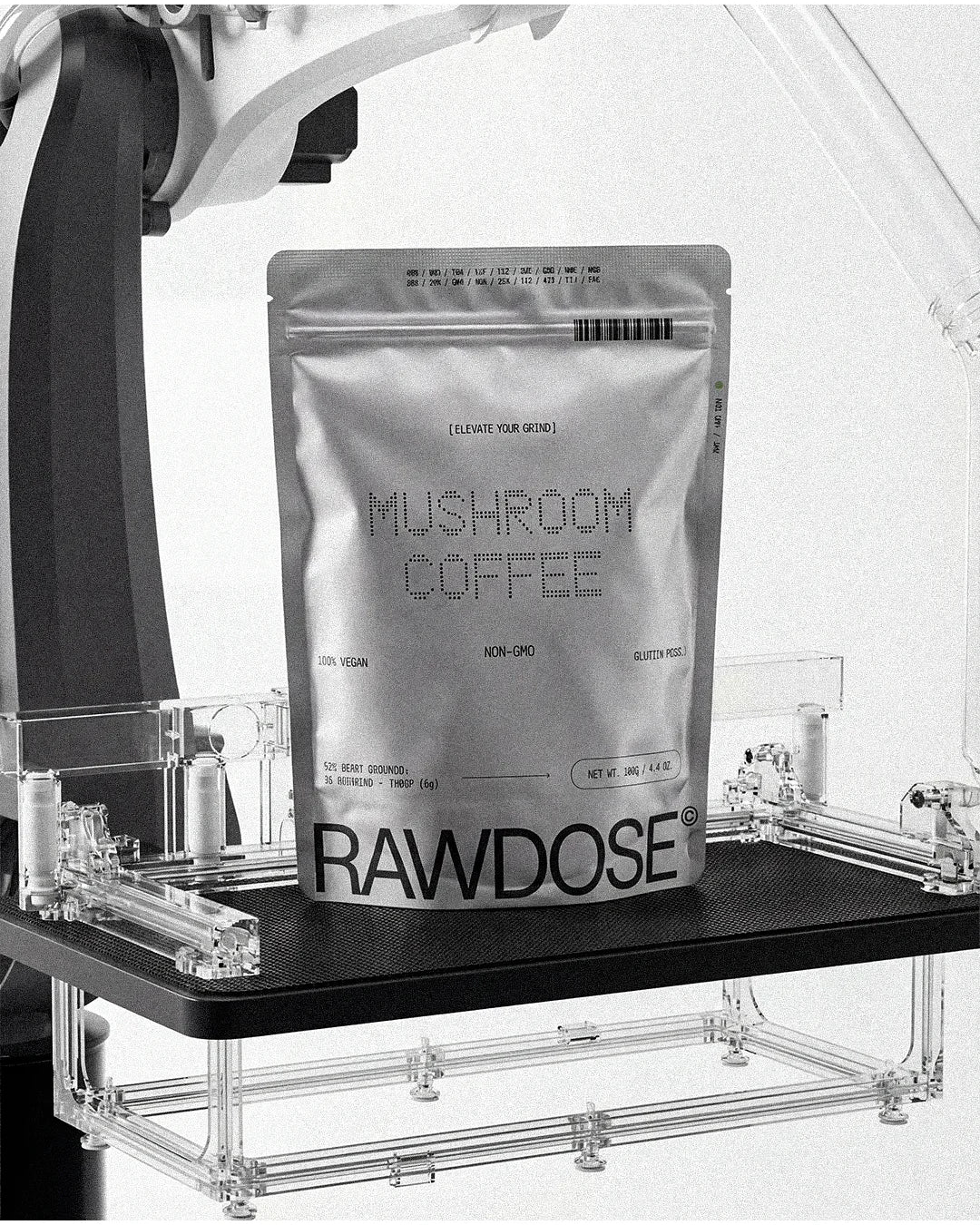 Silver pouch of RAWDOSE mushroom coffee on a black platform with robotic arm in background
