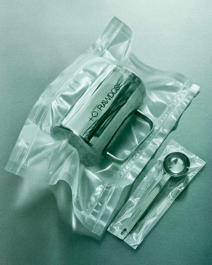 Stainless steel measuring cup and spoon set labeled RAWDOSE packaged in clear vacuum-sealed plastic bags