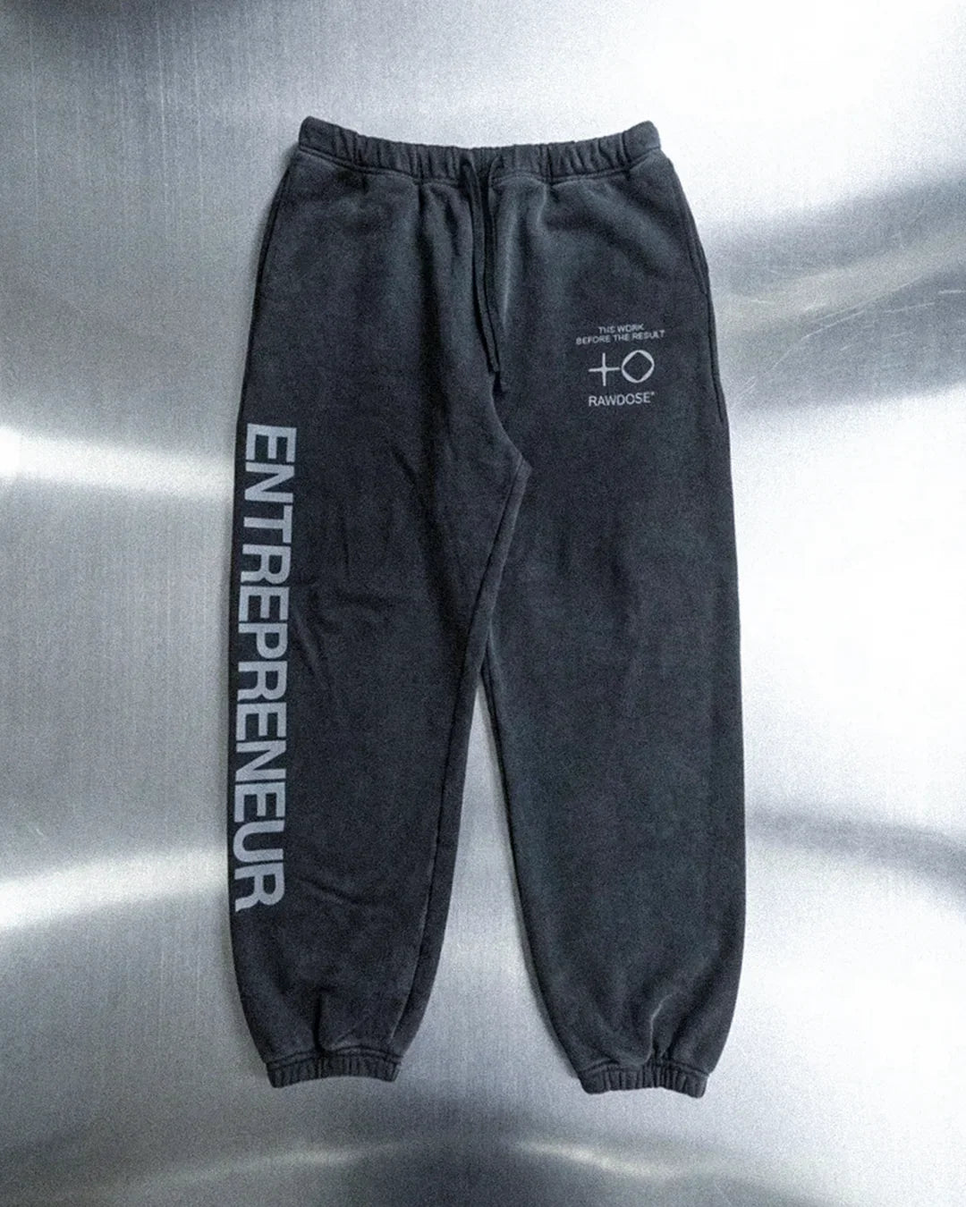 Black sweatpants with elastic cuffs and waistband, featuring ENTREPRENEUR text and RAWOOSE logo
